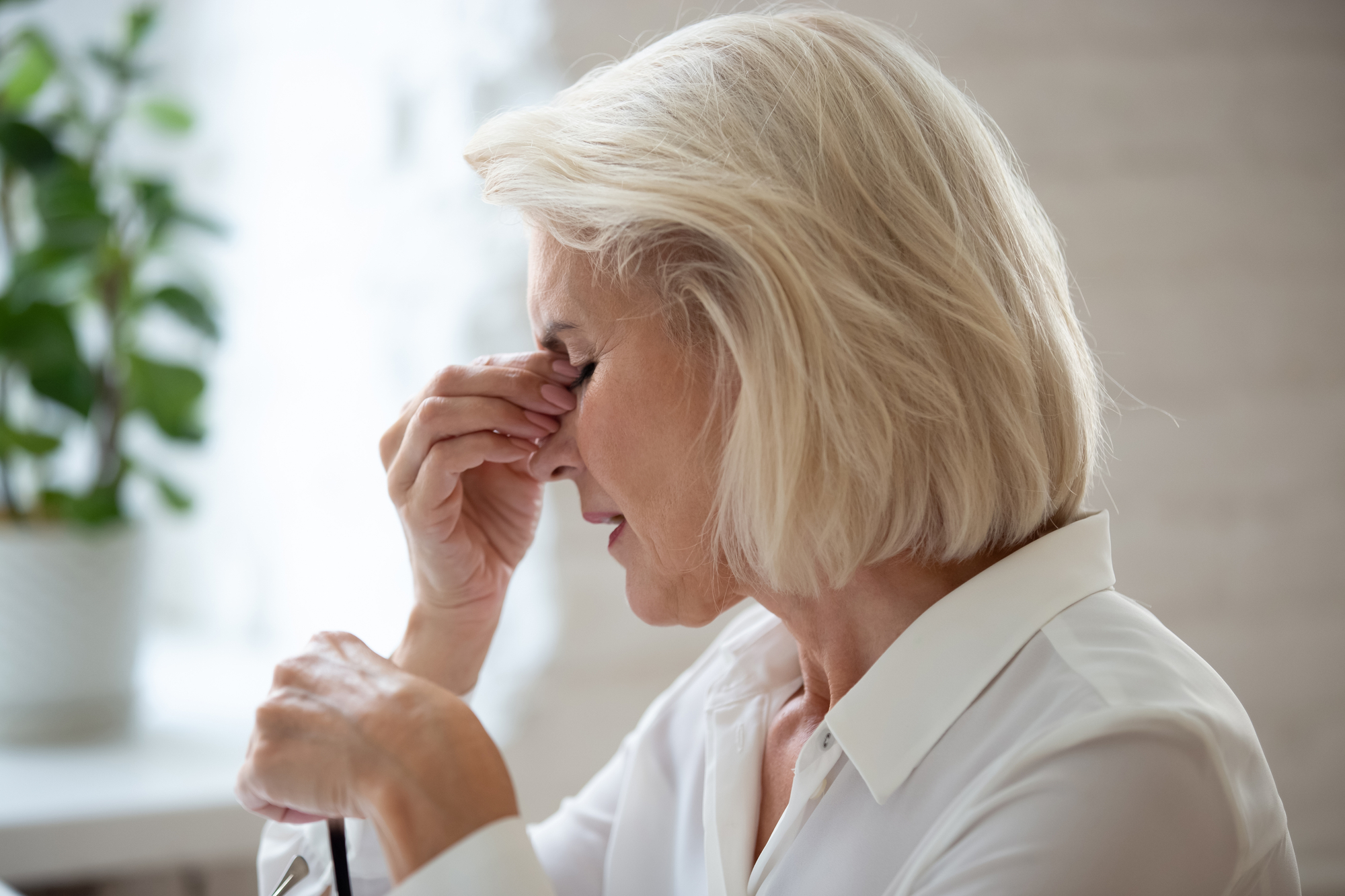 Woman rubbing tired eyes, experiencing fatigue and tension